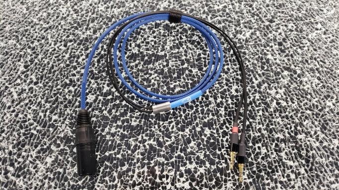 High-quality blue audio cable with XLR and dual 3.5mm jack connectors on patterned surface