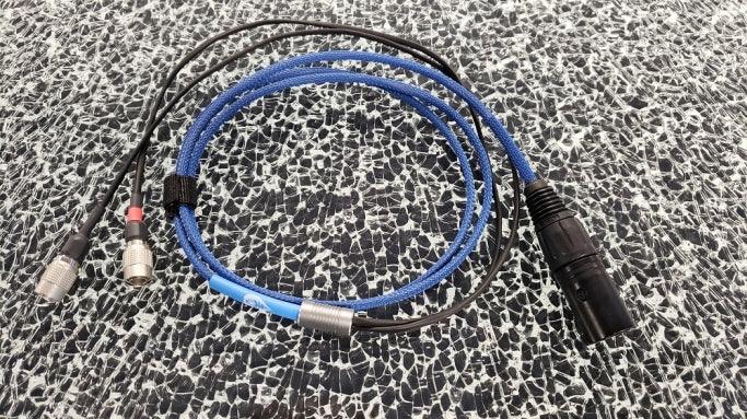 High-quality blue audio cable with XLR and dual 3.5mm jack connectors on patterned surface